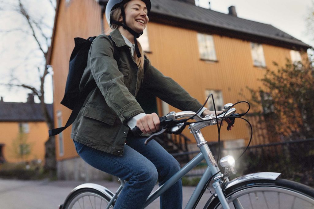 Nainen ajaa hymyillen pyörällä. 