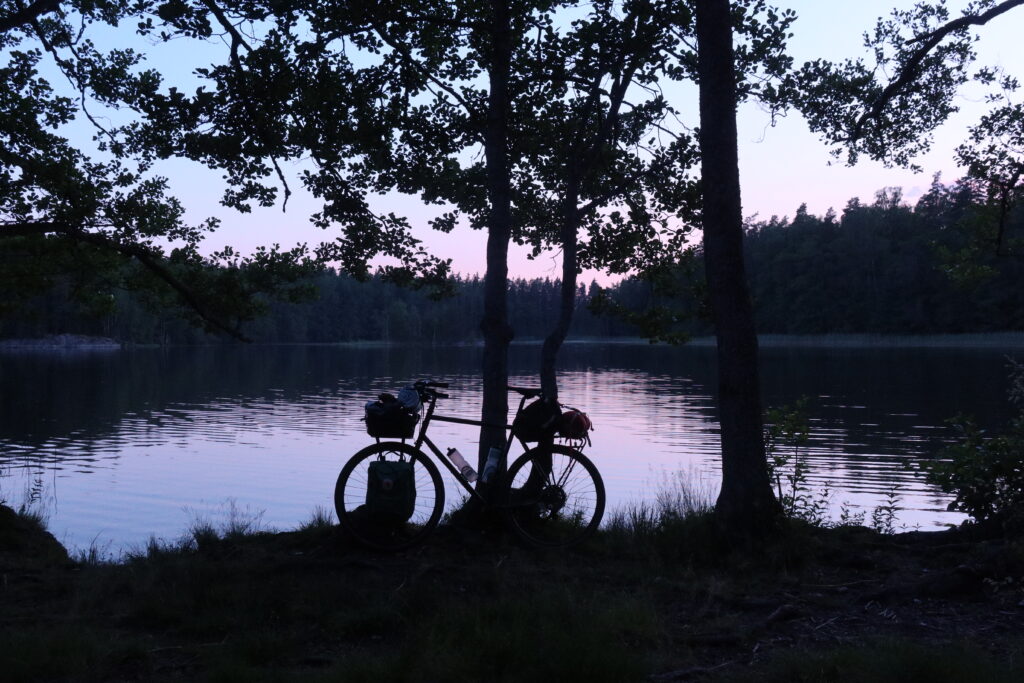 A Pelago tour bike leaning to a tree on a summer night in front of a beautiful lake view.